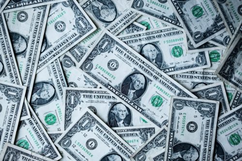 A scattered pile of one-dollar bills featuring the portrait of George Washington lies reminiscent of a scene straight out of Texas. Overlapping, they reveal various serial numbers and treasury seals—bearing a subtle warning in hues of green and white: what you need to know about credit card fraud.