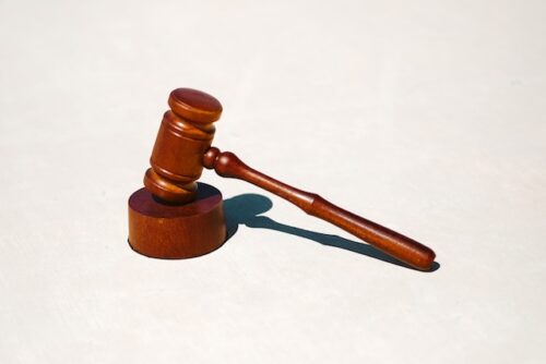 A wooden judge's gavel rests on its sound block against a plain white background, symbolizing the authority and weight of legal procedures.