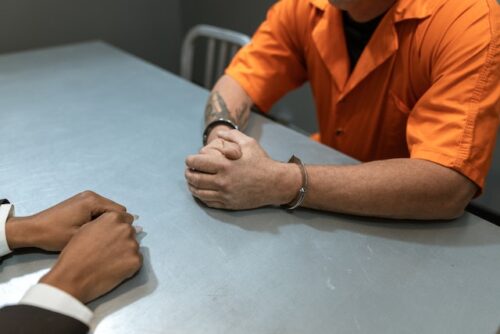 man in handcuffs at table with man in suit