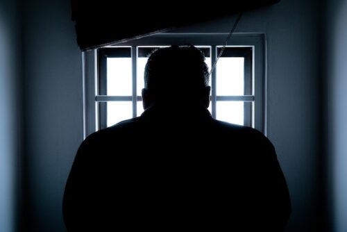 man standing in front of jail window