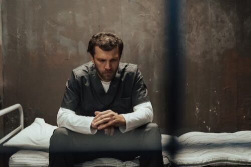 man sitting in jail cell