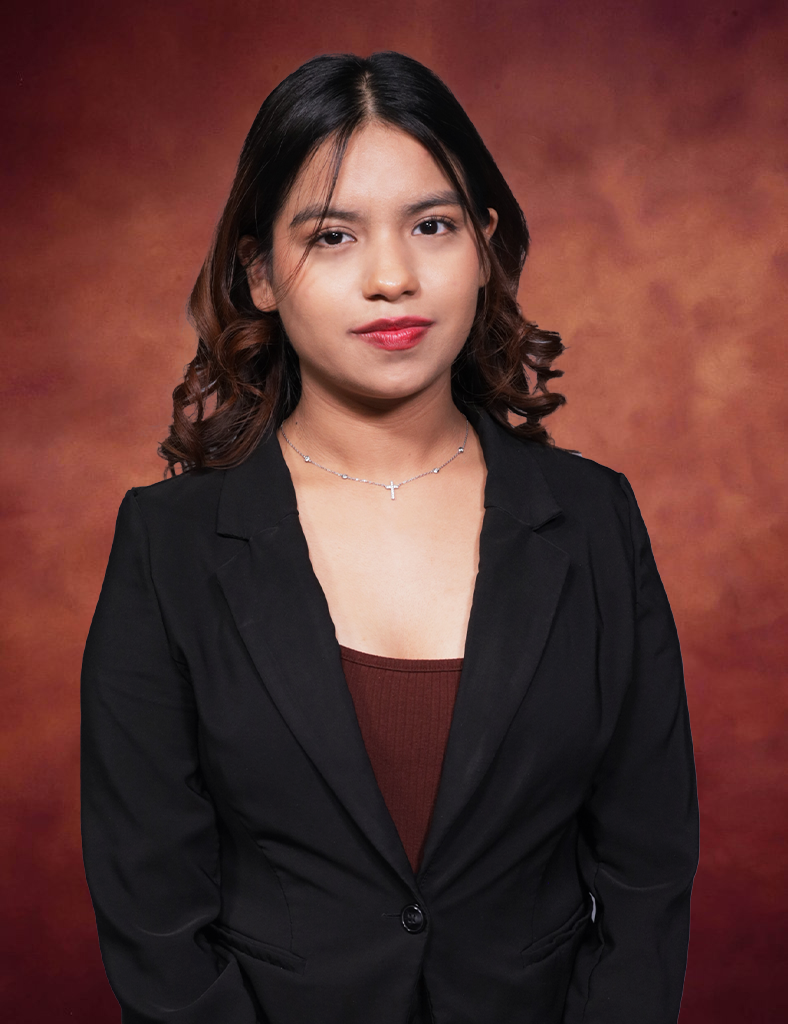 Sesilia Ponce, a woman with long dark hair, wears a black blazer and necklace as she stands confidently against a brown textured background. Her calm expression and direct gaze captivate the viewer's attention.