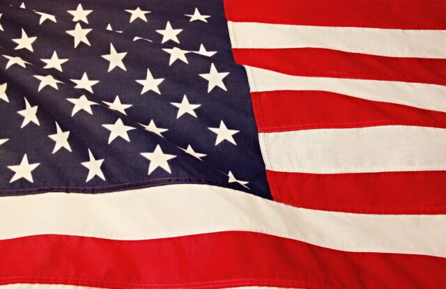 Close-up view of the American flag, featuring a section of the blue field with white stars and red and white stripes in the foreground.