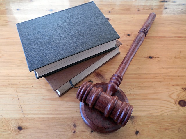A wooden judge's gavel rests on a striking base, placed next to three stacked legal books with textured covers on a wooden table—a symbol of justice that often decides the fate of drunk drivers.