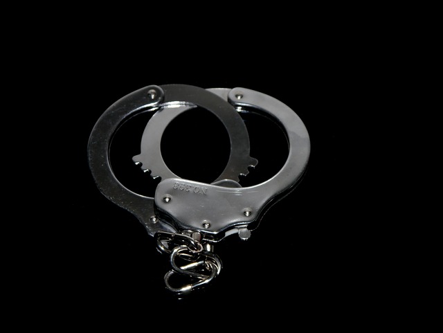 A pair of silver handcuffs is laid out against a black background, symbolizing the boundaries one must adhere to. The open handcuffs, with a small chain connecting the two cuffs, serve as a stark reminder of the legal limit not to be crossed.