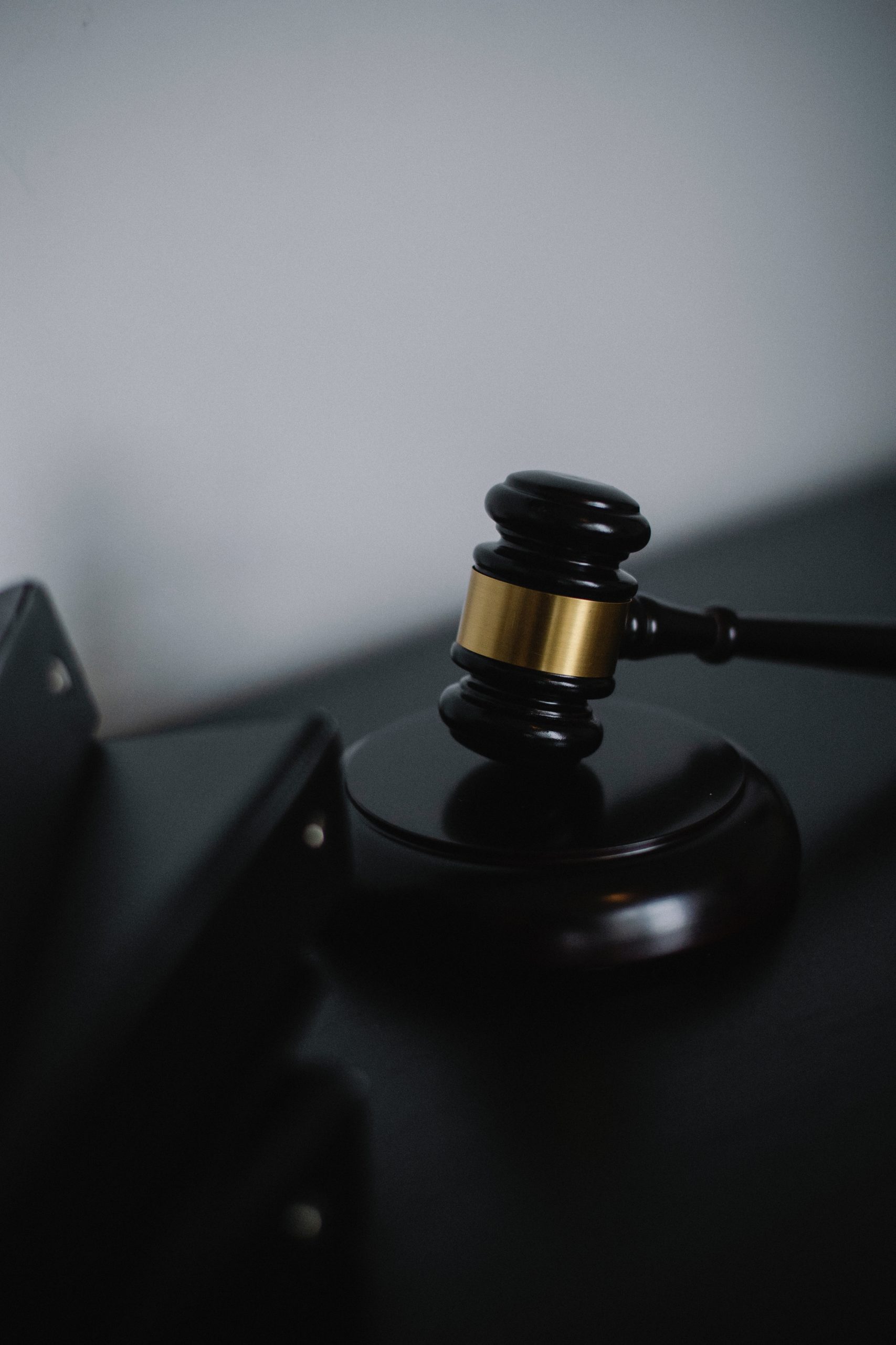 A close-up of a judge's wooden gavel, embellished with a metallic gold accent, resting on a sound block. In the blurred background reminiscent of a Texas firm's chambers, dark surfaces enhance the formality and seriousness, as if preparing for an initial consultation.