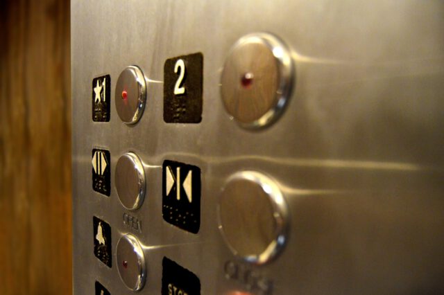Close-up of an elevator panel showcasing metal buttons and illuminated indicators for floors and door controls. With the number 