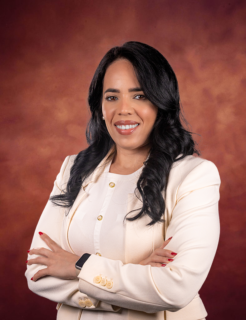 Jessica Rodriguez, a woman with long black hair wearing a cream blazer and white top, stands with arms crossed, smiling confidently against a warm brownish-red background.