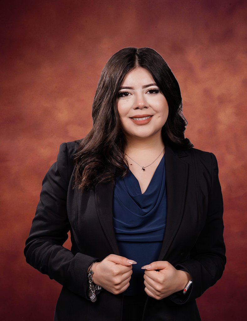 Jennifer Rosales, a woman with long dark hair, wearing a navy blouse and black blazer, smiles at the camera. She stands in front of a warm brown gradient background, holding the lapels of her blazer.